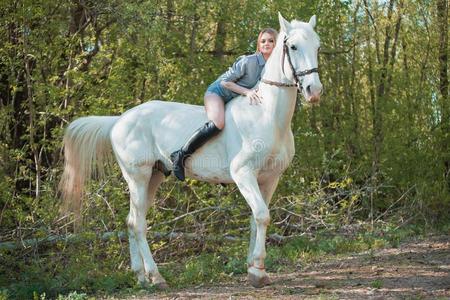 黑头发的妇女女人骑马黑暗的马在夏绿色的森林.照片