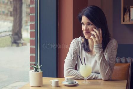 年幼的女人使用智能手机在咖啡馆
