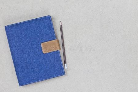 笔记簿遮盖蓝色斜纹粗棉布和空的标签向木制的背景