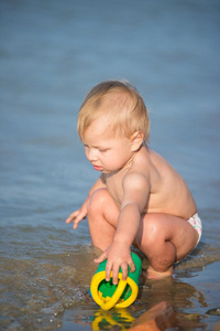 漂亮的婴儿演奏向指已提到的人沙的海滩和采用海水.