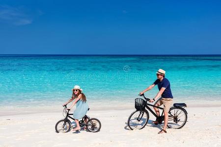 父亲和女儿骑马自行车在热带的海滩