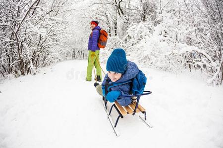 一女人是（be的三单形式运送的一小孩向一雪橇.