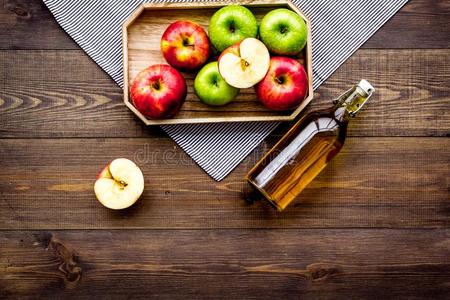 瓶子关于新鲜的苹果汁在近处秋苹果.黑暗的木制的背景