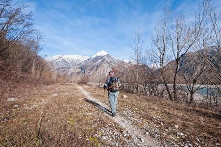 男人远足者步行向跟踪越过河岸对于山.