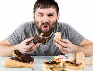 贪食者有胡须的男人吃纸杯蛋糕和狂乱后的长的日常饮食照片