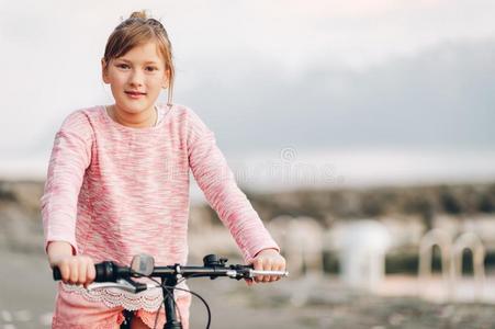 漂亮的小孩女孩骑马自行车紧接在后的向湖