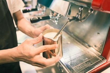 咖啡馆准备咖啡的员工使起泡沫奶在旁边咖啡豆机器和酿酒的声调.