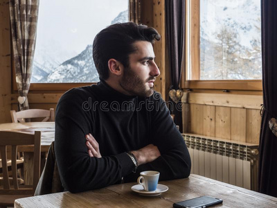 英俊的男人喝饮料咖啡豆采用舒适的滑雪求助