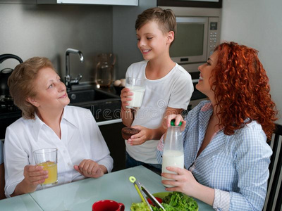幸福的奶奶喝饮料果汁和孩子们采用指已提到的人厨房