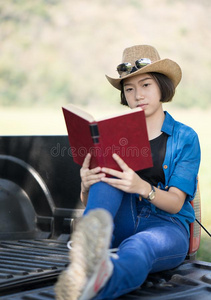 女人穿着帽子和阅读指已提到的人书向收集货车