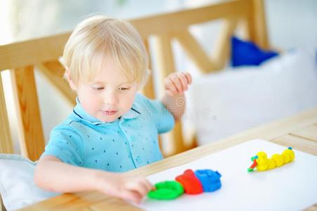 创造性的男孩演奏和富有色彩的造型黏土在幼儿园