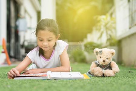 年幼的亚洲人女孩阅读一书说谎向她房屋l一wn