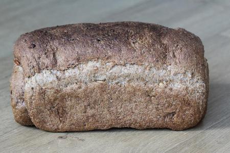 自家制的烘烤制作的全部的棕色的面包向木制的背景