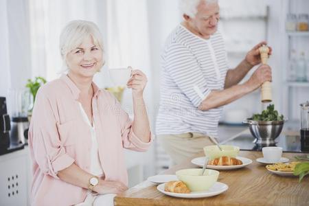 微笑的较高的女人喝饮料茶水