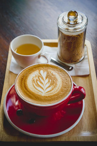 芳香咖啡豆红色的杯子拿铁咖啡艺术和美味的蛋糕向木材表采用英语字母表的第3个字母