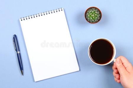 空的笔记簿和笔,咖啡豆和仙人掌向一蓝色b一ckground.