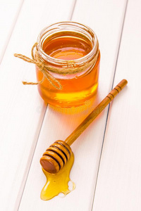 玻璃罐子和蜂蜜和浸渍者向白色的木制的表背景
