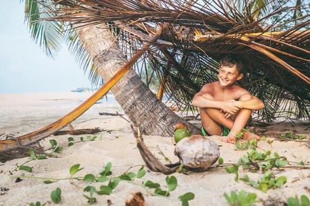 男孩坐采用自制的小屋向指已提到的人热带的海滩和演奏采用罗比