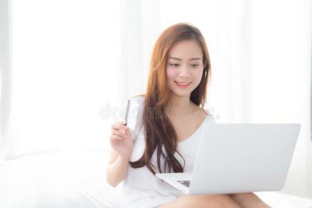 美丽的年幼的亚洲人女人用户信誉卡片和便携式电脑