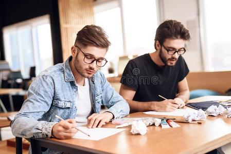 两个自由作家人绘画向纸和铅笔在书桌.