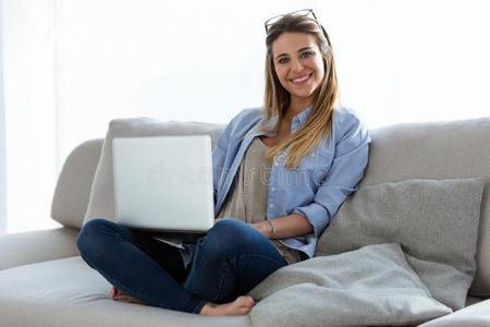美丽的年幼的女人使用她便携式电脑在家.