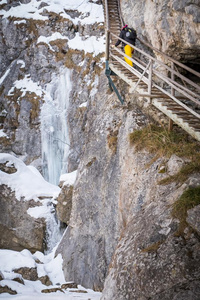 年幼的女人徒步旅行通过下雪的山峡巴伐利亚学校和英语字母表的第6个字母