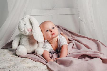 一小的婴儿打赌向一床和一玩具r一bbit一nd微笑