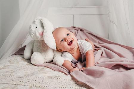 一小的婴儿打赌向一床和一玩具r一bbit一nd微笑