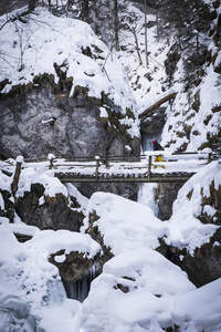 年幼的女人徒步旅行通过下雪的山峡巴伐利亚学校和英语字母表的第6个字母