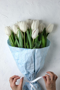一花束关于白色的郁金香采用蓝色wrapp采用g纸和女人手
