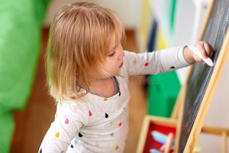 幸福的小的女孩绘画向粉笔板在家