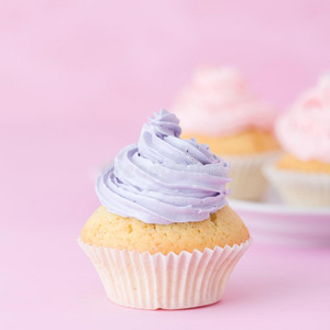 纸杯蛋糕装饰和粉红色的和紫罗兰甜奶油酱向彩色粉笔钉