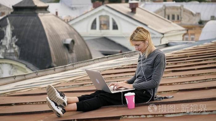 年幼的幸福的女人坐和咖啡豆向指已提到的人屋顶.风吹风