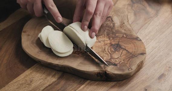 年幼的女性的手限幅意大利干酪奶酪向木制的板