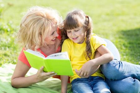母亲阅读一书向小孩在户外采用夏季
