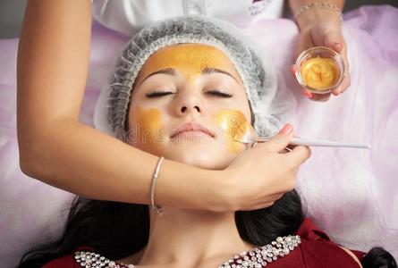 女性的美容品业者是（be的三单形式应用金面具和一软的刷子向