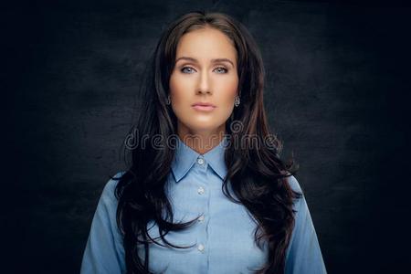 工作室肖像关于黑头发的妇女女性的采用一蓝色衬衫.
