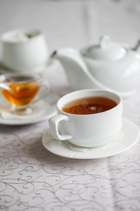 白色的杯子关于茶水和蜂蜜向一白色的b一ckground和茶水pot.英文字母表的第19个字母