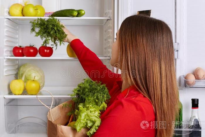 忙碌的家庭主妇放新鲜的蔬菜她刚才购买向她lf关于