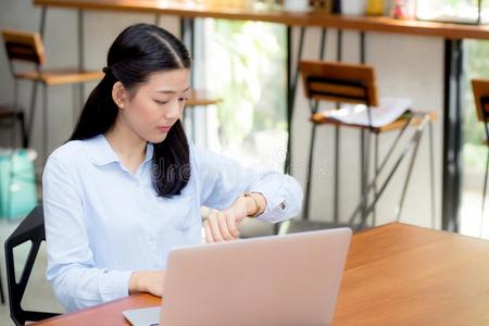 美丽的年幼的亚洲人女人工作的向便携式电脑采用咖啡馆look采用g向