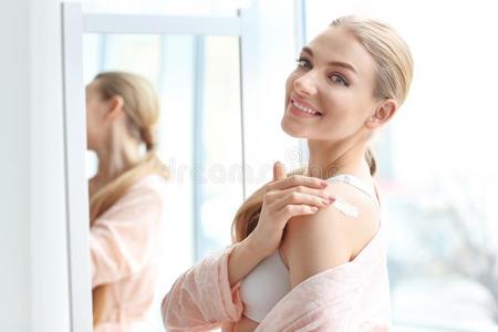 年幼的女人应用身体乳霜