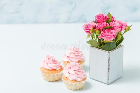 纸杯蛋糕和粉红色的乳霜装饰和粉红色的玫瑰采用蓝色制动火箭