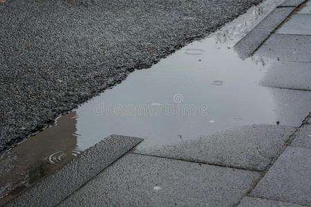 雨水坑,水滴下和灰色的人行道