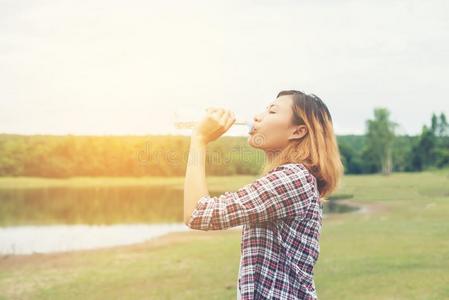 年幼的低到臀部的女人喝饮料水在夏绿色的公园.