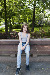年幼的有魅力的女孩一次向长凳.夏公园.微笑.辐透