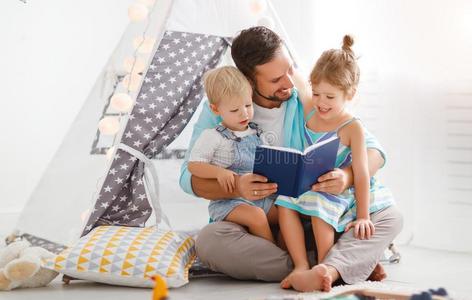 家庭父亲阅读向孩子们书采用帐篷在家