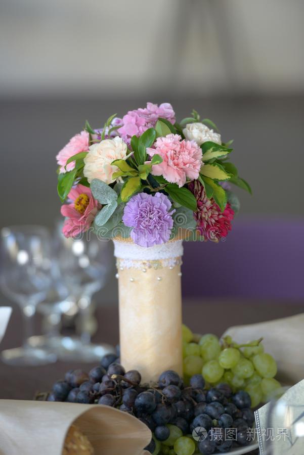 婚礼花的表安排和新鲜的麝香石竹和葡萄