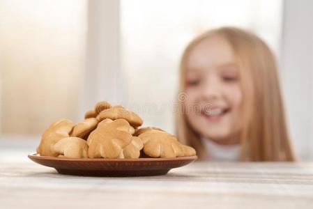 小的女孩是（be的三单形式有样子的向甜的甜饼干和相貌饥饿的.