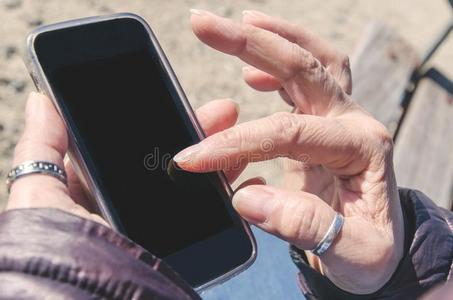 成熟的女人手令人同情的指已提到的人屏幕关于一可移动的电话