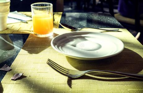 白色的空的盘子和餐叉,勺和桔子玻璃向黄色的英语字母表的第20个字母